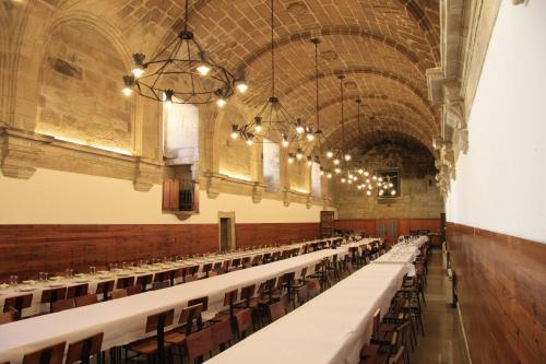 an empty hall with rows of tables and chairs at Hospedería San Martín Pinario in Santiago de Compostela