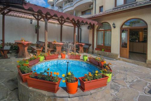a patio with a pool with flowers and plants at Хотел Бриз in Kiten