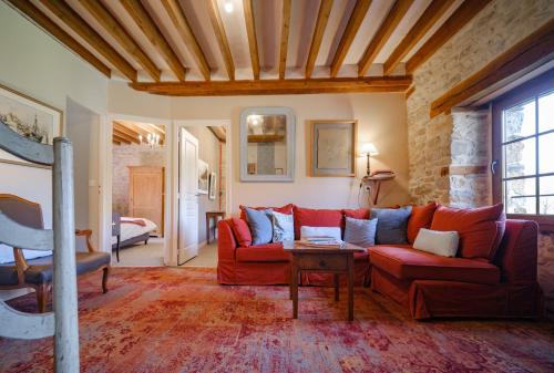 a living room with a red couch and a table at Domaine de la Pommeraye & Spa in La Pommeraye
