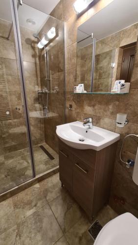 a bathroom with a sink and a shower and a toilet at Pensiunea Mădălina in Durau