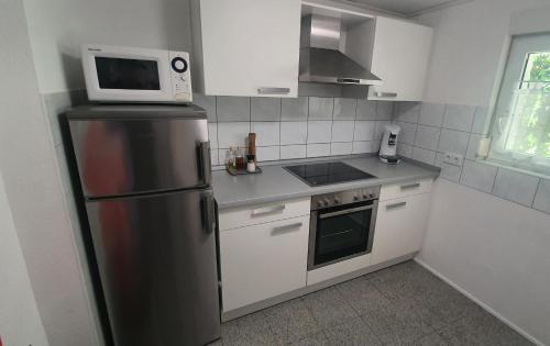 cocina con nevera de acero inoxidable y microondas en Kleines Bauernhaus mit nostalgischem Flair, en Rheinhausen