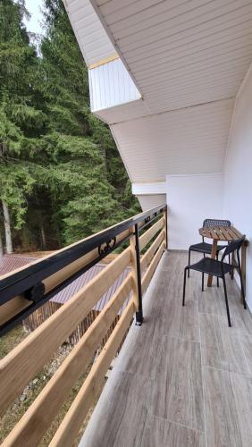 a balcony with a table and a chair on it at Pensiunea Mădălina in Durau