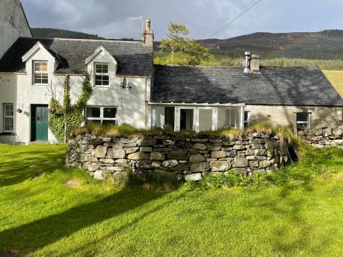 una antigua casa de piedra con una pared de piedra en Inverlael Farm Cottages en Inverlael