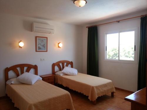two beds in a room with a window at Apartamentos Vista al Puerto in San Antonio Bay