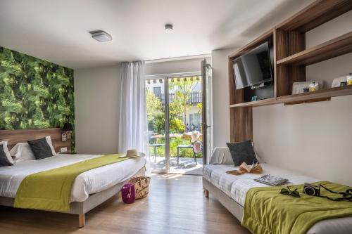 ラ・ロシェルにあるATHOME RESIDENCE ET SPAのベッドルーム1室(ベッド2台、壁掛けテレビ付)