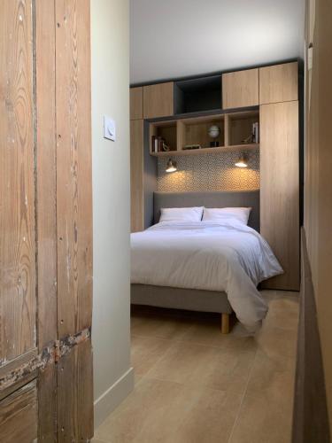 Appartement Escapade Marine - Maison d Aligre في مارانس: غرفة نوم بسرير مع جدار خشبي