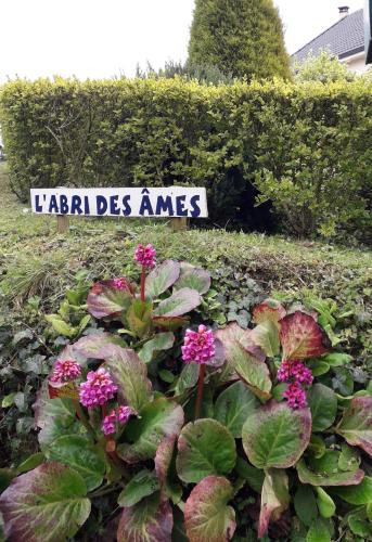 un panneau dans un jardin avec des fleurs devant lui dans l'établissement L'ABRI des ÂMES, à Gerponville