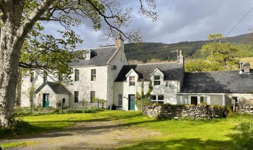 ein großes weißes Haus mit einer Steinmauer in der Unterkunft Inverlael Farm Cottages in Inverlael