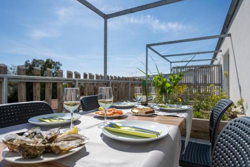 a table with food and wine glasses on a patio at ATHOME RESIDENCE ET SPA in La Rochelle