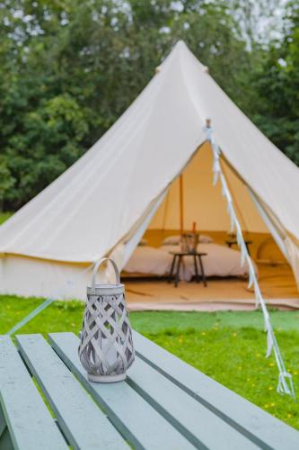 a vase sitting on a picnic table in front of a tent at Duneden Belle Glamping in Randalstown