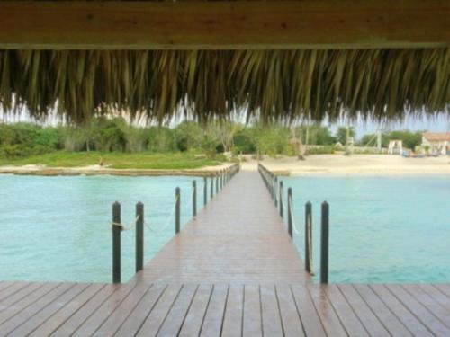a wooden boardwalk leading to a beach with a pier at Appartamenti in Cadaques Caribe in Bayahibe