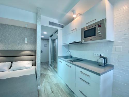 a white kitchen with a sink and a microwave at My Sunshine Apartments in Batumi in Batumi