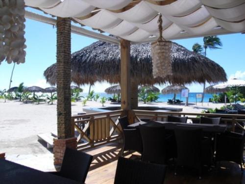 a restaurant with chairs and a straw umbrella on the beach at Appartamenti in Cadaques Caribe in Bayahibe