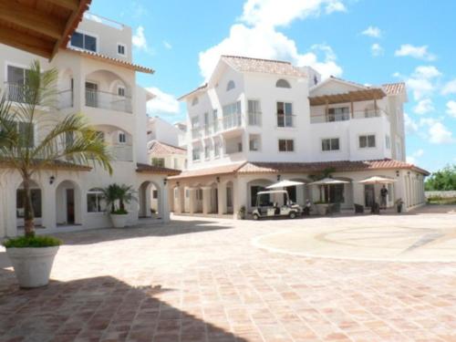 a large white building with a palm tree in front of it at Appartamenti in Cadaques Caribe in Bayahibe