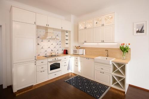 a white kitchen with white cabinets and a sink at Captain's Suite in Neusiedl am See