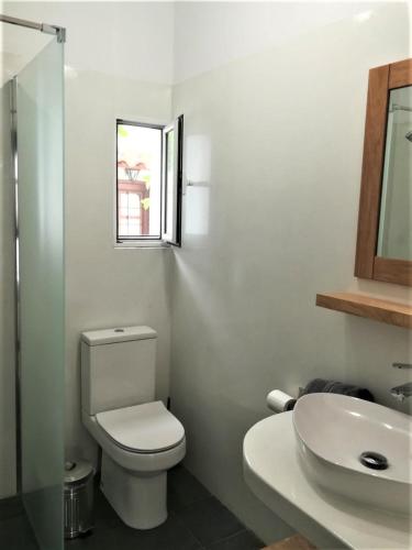 a white bathroom with a toilet and a sink at Almira Kalamos in Kálamos