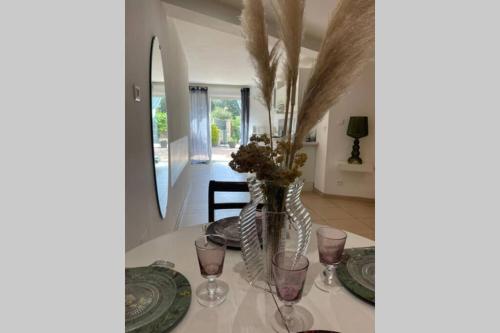 une table avec des verres et un vase avec des fleurs dedans dans l'établissement Appartement avec jardin -alentours Ajaccio centre, à Alata