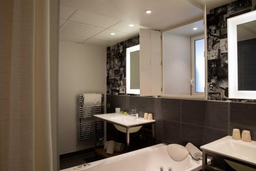 a bathroom with two sinks and a tub and a mirror at Hôtel et Spa La Villa K - Basel Airport in Saint-Louis