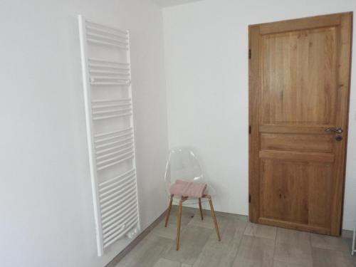 a room with a wooden door and a chair next to a wall at Gîte La Peyre in Le Grand-Bourg