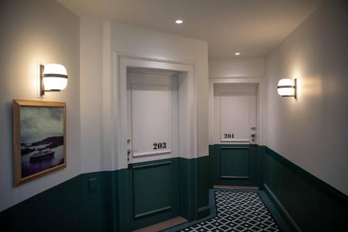 a hallway with green doors and numbers on the wall at Hôtel et Spa La Villa K - Basel Airport in Saint-Louis