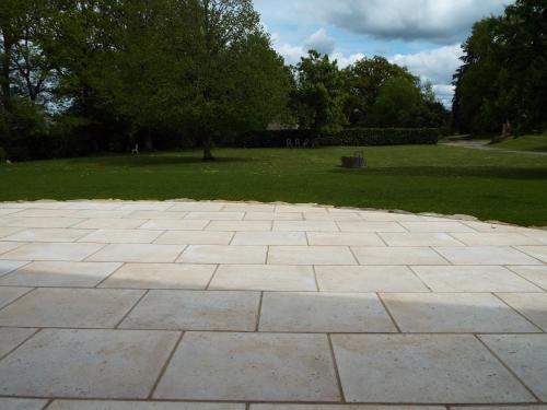 a stone patio in a park with trees and grass at Gîte La Peyre in Le Grand-Bourg