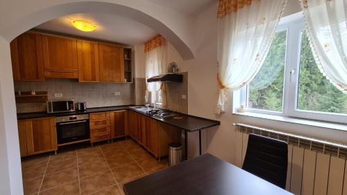 a kitchen with wooden cabinets and a large window at Pensiunea Mădălina in Durau