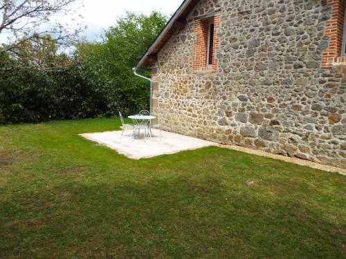 a table and chairs in front of a stone building at Gîte La Peyre in Le Grand-Bourg