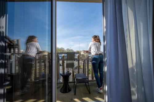 a woman standing on a balcony looking out the window at ATHOME RESIDENCE ET SPA in La Rochelle
