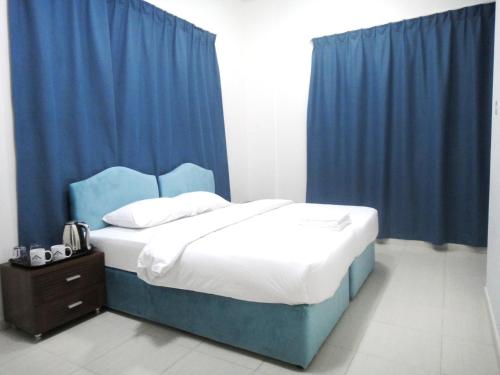 a bedroom with a bed with blue curtains at Al Badaa Star Residence - Home Stay in Dubai