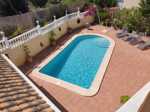 a swimming pool next to a house with a white fence at Villa Castillo Nuevo with optional Heated Private Pool in San Miguel de Salinas