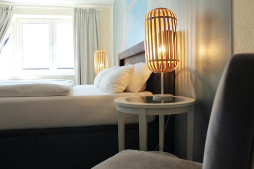 a bedroom with a bed and a table with a lamp at Hotel-Pension Am Fuchsberg in Bad Doberan