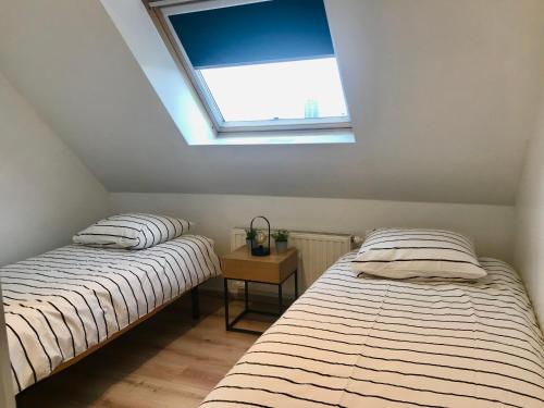 two twin beds in a room with a window at Appartement Cousteau - Terras, Zeezicht, Marina in Ostend