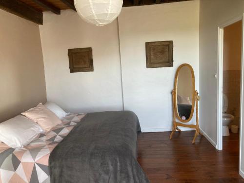 um quarto com uma cama e um espelho em L'Intemporelle em Ozourt