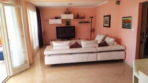 a living room with a white couch and a television at Villa Goda in Tučepi