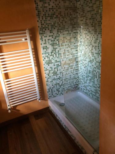 a bathroom with a tub with a window and a tile wall at Corte Fratini Appartamenti in Trevi
