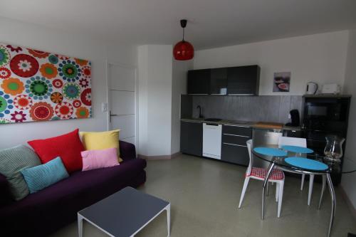un salon avec un canapé et une table et une cuisine dans l'établissement Cottages de la ville Daniou, à Langrolay