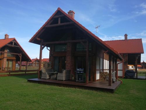 a small house with a large deck in the grass at Leśna Ostoja in Borowy Młyn