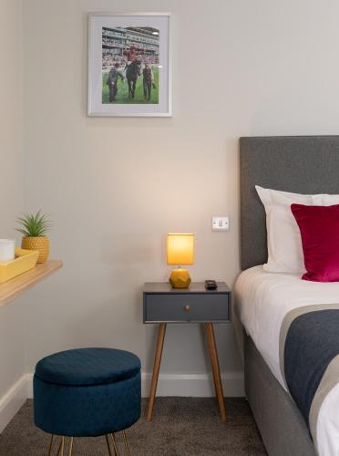 a bedroom with a bed with a blue stool and a table at Stableside Hostel at York Racecourse in York