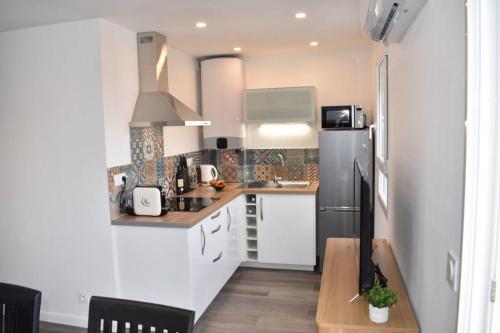 Il comprend une cuisine équipée d'un réfrigérateur noir et de placards blancs. dans l'établissement Confort et calme au sud de Bastia, à Bastia