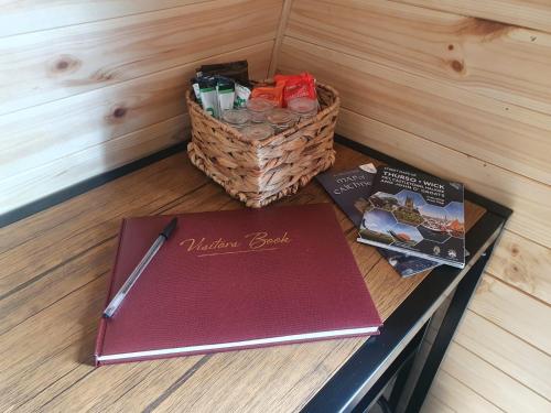 a table with a notebook and a basket of books at North Point Pods NC500 in Thurso