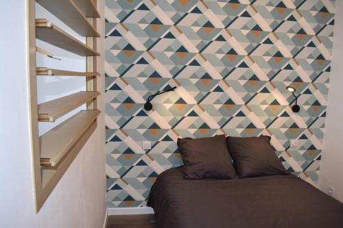 ein Schlafzimmer mit einer Wand mit geometrischen Akzenten und einem Sofa in der Unterkunft Confort et calme au sud de Bastia in Bastia