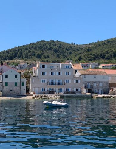 a small boat in the water in front of a building at Plateau in Vis