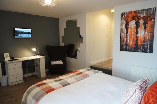 a bedroom with a bed and a desk and a painting at VIP Church View Apartment in Portadown