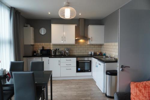 a kitchen with white cabinets and a black table at VIP Church View Apartment in Portadown