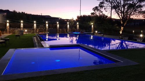 a large swimming pool with blue water at night at Orion Eco Suites in Karteros