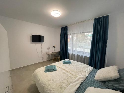 a bedroom with a bed and a desk and a window at Castle Residence apt. Zamorei in Buşteni