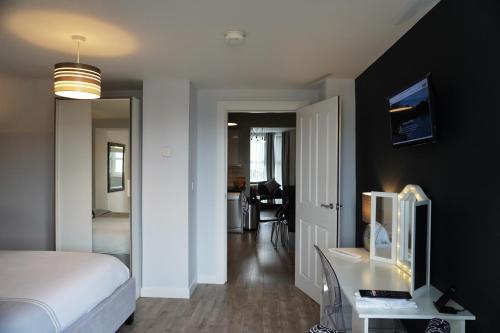 a bedroom with a bed and a desk with a television at VIP Church Street Apartment in Portadown