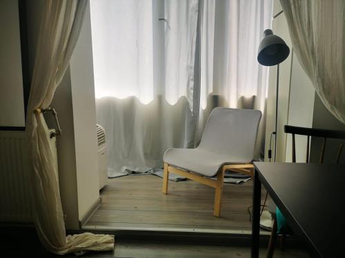 una silla blanca sentada frente a una ventana en Old Town Studio, en Bucarest