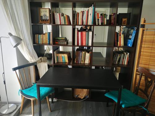 una mesa negra y dos sillas frente a un estante de libros en Old Town Studio, en Bucarest