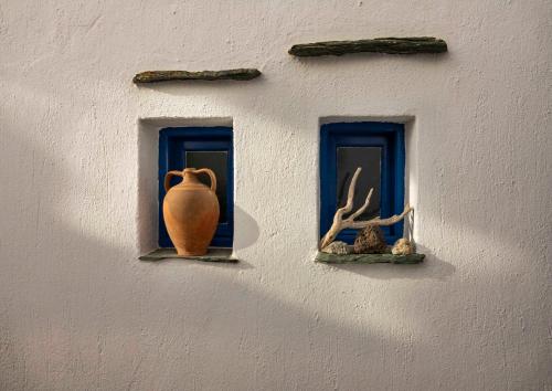 a wall with two windows and a vase on it at Meltemi in Chora Folegandros